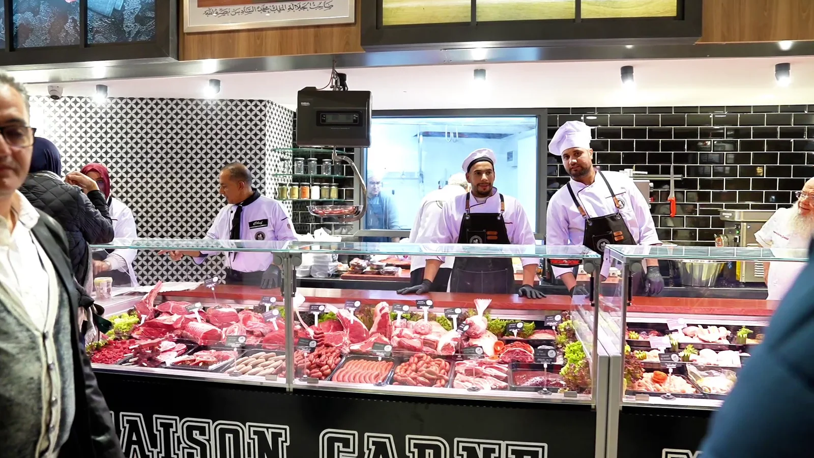 Counter of a Maison Carne butcher shop, staff and customers