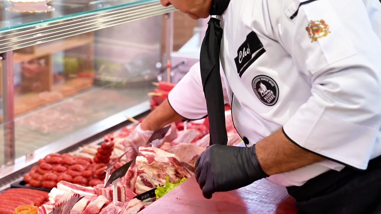 Butcher preparing and cutting meat at the counter